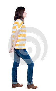 Back view of standing young beautiful brunette woman in yellow