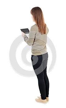 Back view of standing young beautiful girl with tablet computer