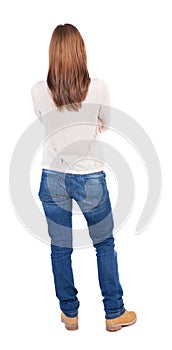 Back view of standing young beautiful woman in jeans.