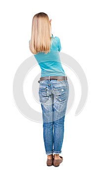 Back view of standing young beautiful woman in jeans.