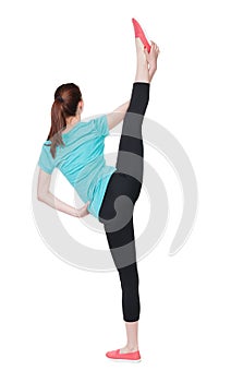 Back view of standing young beautiful woman in sport dress involved in Pilates.