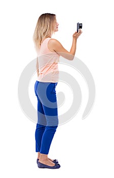 Back view of standing young beautiful woman and using a mobile