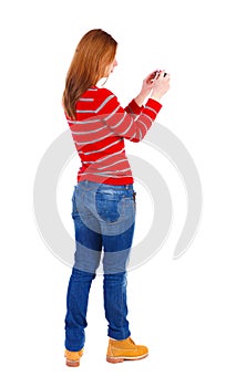 Back view of standing young beautiful woman and using a mobile