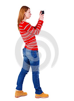 Back view of standing young beautiful woman and using a mobile