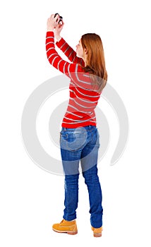 Back view of standing young beautiful woman and using a mobile