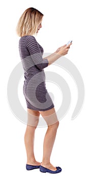 Back view of standing young beautiful woman using a mobile phon