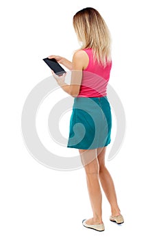 Back view of standing young beautiful woman using a mobile phon