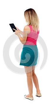 Back view of standing young beautiful woman using a mobile phon