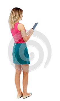 Back view of standing young beautiful woman using a mobile phon