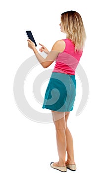 Back view of standing young beautiful woman using a mobile phon