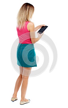 Back view of standing young beautiful woman using a mobile phon