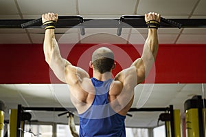 Back view of strong male athlete with perfect muscles training, doing exercises