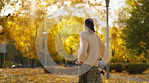 back view stunning young brunette woman joyfully running in autumn park with yellow foliage. happy attractive girl in