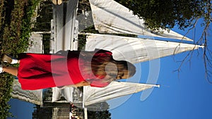 Back view of stylish woman walking in yacht club with sailing boat on the lake