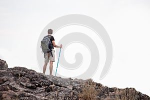 Back view of Success Hiker man standing  on the top mountain with walking pole after hiking to goal . achievement adventure