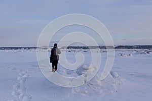 Back view of tall warmly dressed man walking on icy beach with couple in soft focus background