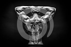 Back view of tattoed bodybuilder with outstretched arms