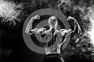 Back view of tattoed bodybuilder with outstretched arms