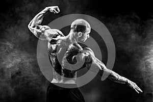 Back view of tattoed bodybuilder with outstretched arms