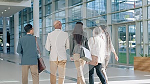 Back view, team and business people walking and talking as travel or commute to office building together in the morning