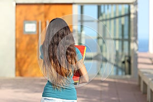 Back view of a teen girl walking towards the school