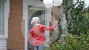 Back view teenage Caucasian girl on autumn spring day outdoors with white balloons. Confident female adolescent eco