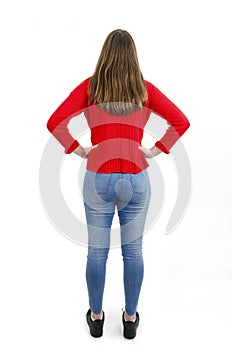 Back view of teenage girl with hands on hips looking at wall. Rear view.