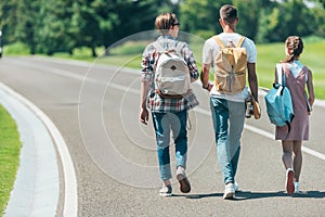 back view of teenage students with backpacks walking together