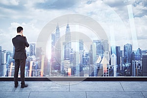 Back view of thoughtful businessman looking at city view with forex chart. Trade and market concept. Double exposure