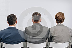 back view of three businessmen sitting on chairs during training