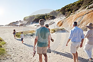 Back view of three generation white family exploring together on a sunny beach