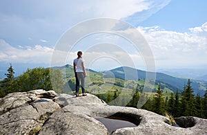 Young woman resting on a big stone in the summer day in the Carpathian mountains