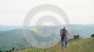 back view of a tourist man with a large backpack in the mountains looks at the peaks. man hiking in the rain with a