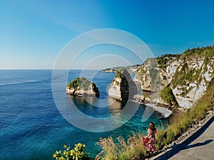 Back view of tourist woman enjoying of tropical beach, sea rocks and turquoise ocean, blue sky. Atuh beach, Nusa Penida