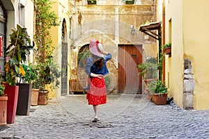 Back view of tourist woman holding hat at Trastevere in Rome, Italy.