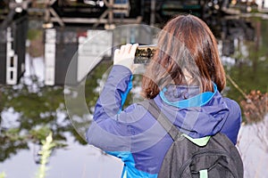 Back view tourist woman take phone photo picture in pine forest of the Talaris Marina Lacanau France