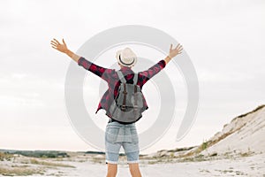 Back view, traveler man , raising his hands up on the trail on the top of the mountain, Tourist on top of high rocks