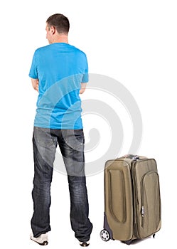 Back view of traveling man with suitcase looking up.