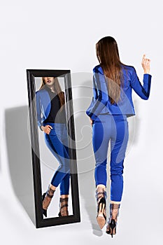 Back view of trendy girl in pantsuit and tulle socks near the mirror