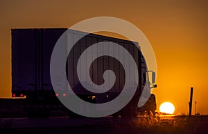 Back view of truck parked in front of sun during sunset
