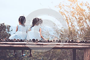 Back view of two child girls sitting and looking at nature