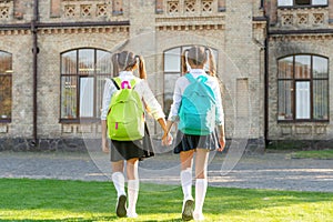 back view of two children with school backpack walking together outdoor