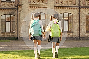 back view of two children with school backpack walking together outdoor