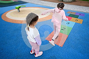 Back view of two girls playing hopscotch game at playground