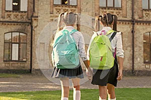 back view of two schoolgirls with school backpack walking together outdoor. copy space