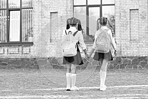 back view of two students with school backpack walking together outdoor