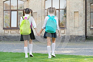 back view of two teen kids with school backpack walking together outdoor