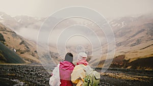 Back view of two traveling woman with map walking in the mountains. Tourists with backpacks try to find way in Iceland.