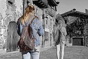 Back view of two women walking in old medieval village.Creative black and white photo with selective effect color in duplicated