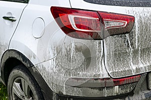 Back view of a very dirty car. Fragment of a dirty SUV. Dirty headlights, wheel and bumper of the off-road car with swamp splashes